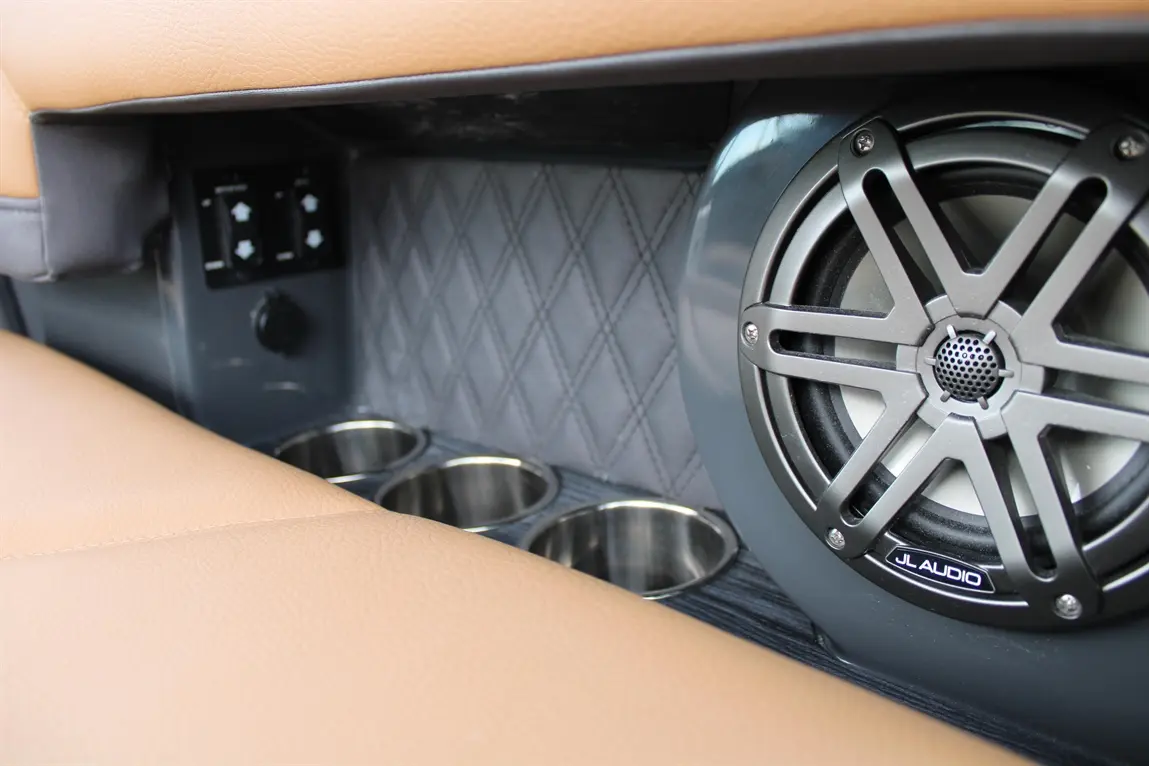 Stylish car interior featuring a JL Audio speaker, cup holders, and control switches mounted on a textured surface.